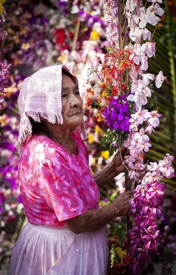 an older woman holding a bunch of flowers at Alcoba independiente en nuestro hogar santa Elena encantada in Santa Elena