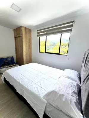 a bedroom with a large white bed with a window at Apartamento Cocorna Aventura in Cocorná