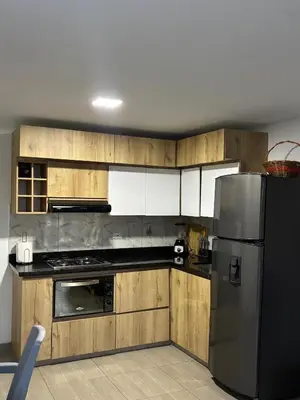 a kitchen with wooden cabinets and a stainless steel refrigerator at Apartamento Cocorna Aventura in Cocorná