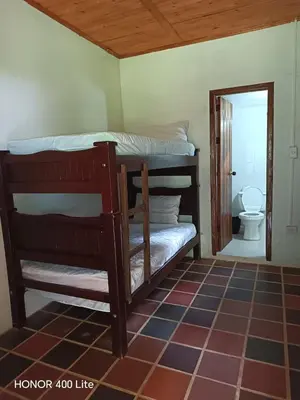a bedroom with bunk beds and a bathroom with a toilet at Reserva El Paujil in Puerto Boyacá