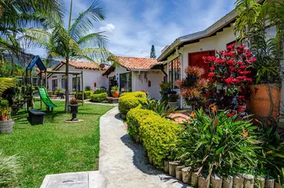 a house with a garden with flowers and plants at Hotel Campestre Santa M de las Aguas in Guatapé