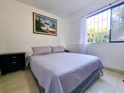 a white bedroom with a bed and a window at Hostal Casa Coliving Laureles Medellin in Medellín