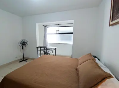 a bedroom with a bed and a window with a fan at Hostal Casa Coliving Laureles Medellin in Medellín