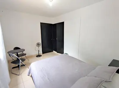 a white bedroom with a bed and a chair at Hostal Casa Coliving Laureles Medellin in Medellín