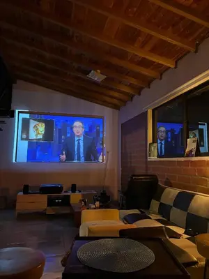 a living room with a tv with two men on it at Villa with Spectacular Medellin View with Pool and Mini Basket-Futbol Field in Medellín