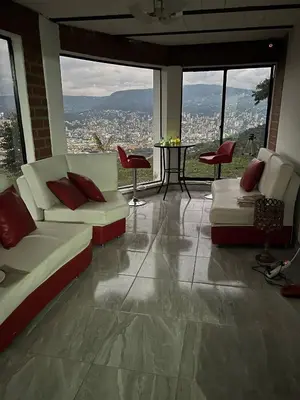 a living room with couches and a table and windows at Villa with Spectacular Medellin View with Pool and Mini Basket-Futbol Field in Medellín