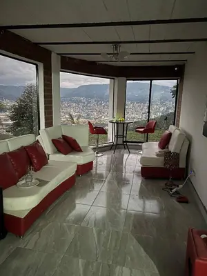a living room with couches and a view of a city at Villa with Spectacular Medellin View with Pool and Mini Basket-Futbol Field in Medellín