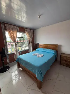 a bedroom with a blue bed and two windows at Casa Amoblada Acogedora para familias in Norcasia