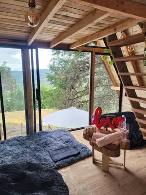 a room with a bed and a chair and a window at Aguapá Glamping in Guarne