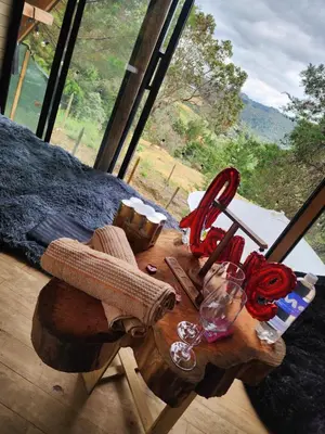 a wooden table with wine glasses on it next to a window at Aguapá Glamping in Guarne