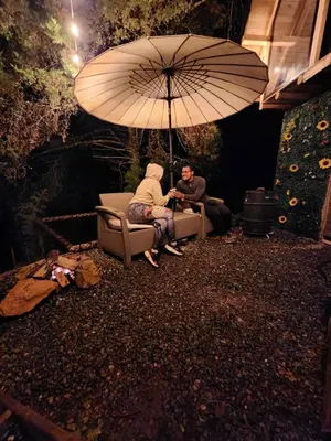 two people sitting in chairs under an umbrella at Aguapá Glamping in Guarne