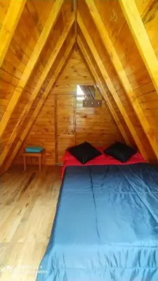 a bed in a wooden room with a roof at Finca Las Palmas - San Luis in San Luis