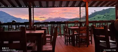 a restaurant with tables and chairs and a view of mountains at Hotel Casa Campestre in Jardin