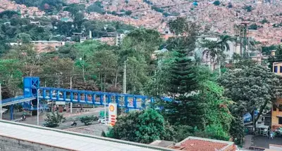 a blue train traveling through a city with trees at Beautiful Duplex Apt in Cabañas Bello Antioquia in Medellín