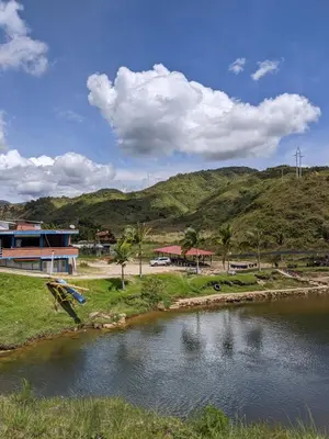 a river in front of a building and a mountain at Centro Turístico Paraíso del Nare in Alejandría