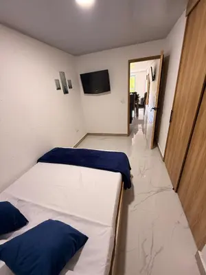 a bedroom with two beds and a television on the wall at Apartamento céntrico, Guatape, cerca al malecon in Guatapé