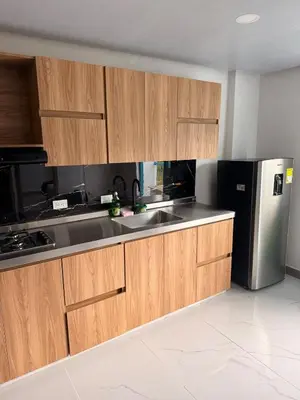 a kitchen with wooden cabinets and a stainless steel refrigerator at Apartamento céntrico, Guatape, cerca al malecon in Guatapé