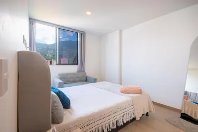 a bedroom with a bed and a large window at Modern apartment - Pool, Gym, and Coworking Space in Envigado
