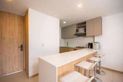 a kitchen with a white counter and stools at Modern apartment - Pool, Gym, and Coworking Space in Envigado