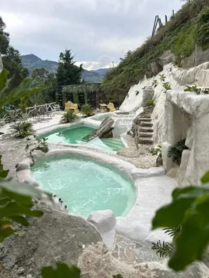 a swimming pool with green water in a mountain at templo de piedra refugio espiritual in Guatapé