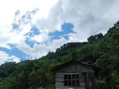 a small wooden building in front of a mountain at La Rana Azul - Hospedaje rural in Manizales