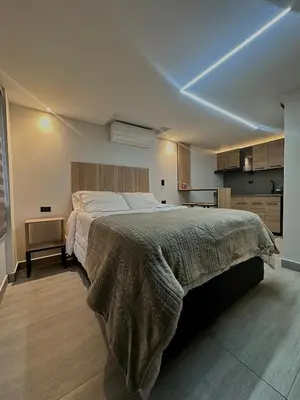 a bedroom with a large bed and a kitchen at Garden Studio Laureles in Medellín