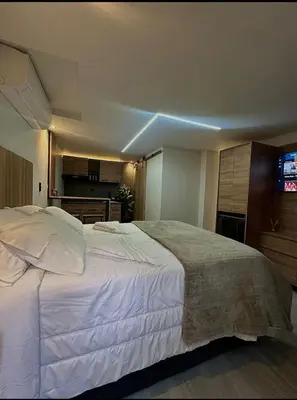 a large white bed in a room with a television at Garden Studio Laureles in Medellín