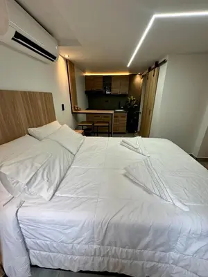 a large white bed in a room with a kitchen at Garden Studio Laureles in Medellín