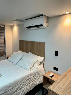 a bedroom with a bed and a tv on the wall at Garden Studio Laureles in Medellín