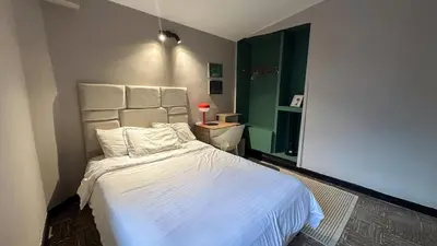 a bedroom with a white bed and a green window at Casa Tuti Laureles in Estación El Salto