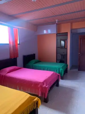 a room with two beds with colorful covers in it at Casa Hotel La Cascada