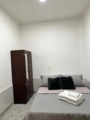 a bed with two pillows and a cabinet in a room at Casa espaciosa cerca al estadio in Medellín