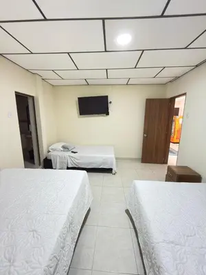 a room with two beds and a flat screen tv at Hotel Plaza de Toros in Manizales