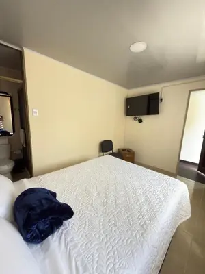 a bedroom with a white bed with a blue blanket on it at Hotel Plaza de Toros in Manizales
