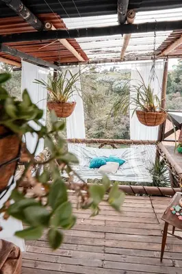 a porch with plants in baskets and a mattress at Almaia 17 in Rionegro