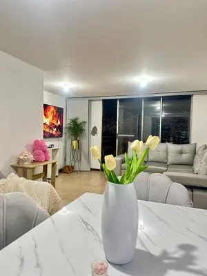a white vase with flowers on a table in a living room at Apartment near Atanasio Girardot Stadium in Medellín