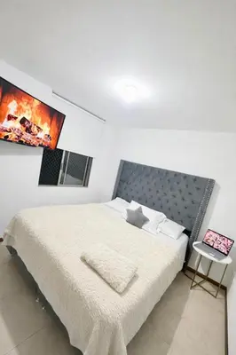 a bedroom with a white bed with a picture on the wall at Apartment near Atanasio Girardot Stadium in Medellín