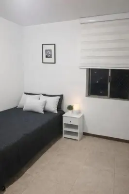 a bedroom with a bed with a night stand and a window at Apartamento cerca del estadio de Medellín in Medellín