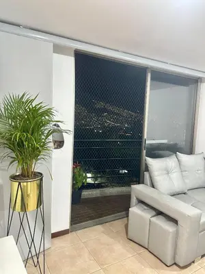 a living room with a white couch and a large window at Apartamento cerca del estadio de Medellín in Medellín