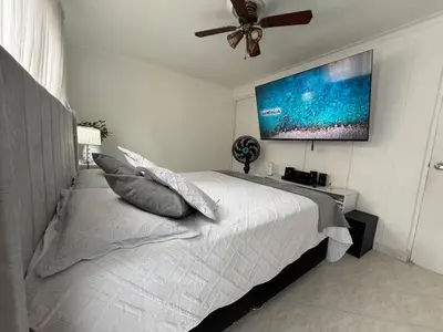 a bedroom with a large bed with a ceiling fan at Happy home in Guayaquil