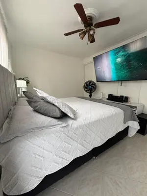 a bedroom with a white bed with a ceiling fan at Happy home in Guayaquil