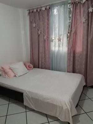 a bed in a room with a window with pink curtains at Abis in Medellín