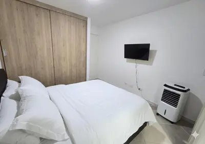 a bedroom with a white bed and a television at Laureles70 in Medellín