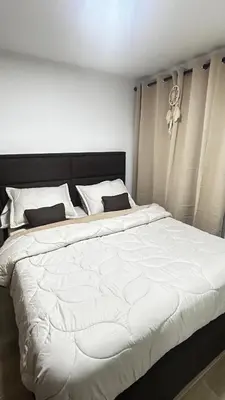 a large white bed with a black headboard in a bedroom at Elena house in Medellín