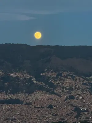 a full moon rising over a city in the sky at Elena house in Medellín