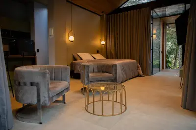 a bedroom with a bed and a table and chairs at Selvva suites cabaña de lujo romántica con jacuzzi in Rionegro