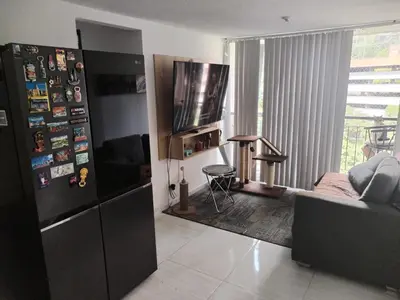 a living room with a black refrigerator and a couch at Apt en sabaneta in Sabaneta