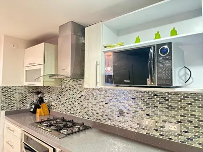 a kitchen with a microwave and a stove top oven at Apartamento familiar en el Poblado Medellín in Medellín