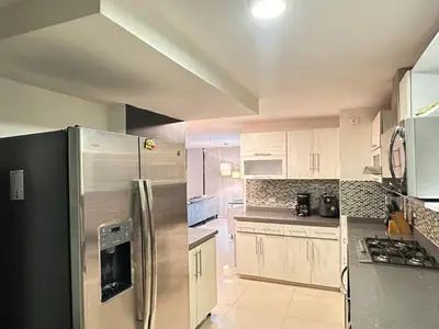a kitchen with white cabinets and a stainless steel refrigerator at Apartamento familiar en el Poblado Medellín in Medellín