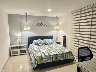 a bedroom with a bed and a night stand and a table at Apartamento familiar en el Poblado Medellín in Medellín